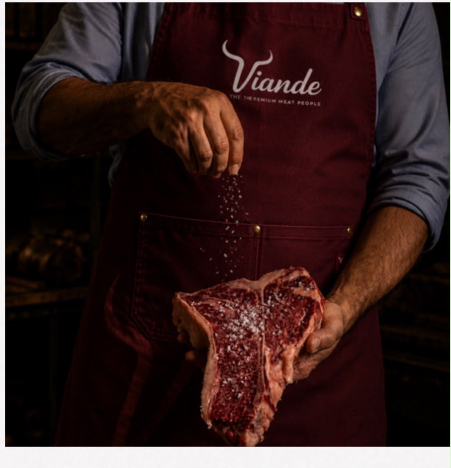 Viande butcher salting a fresh T-bone steak